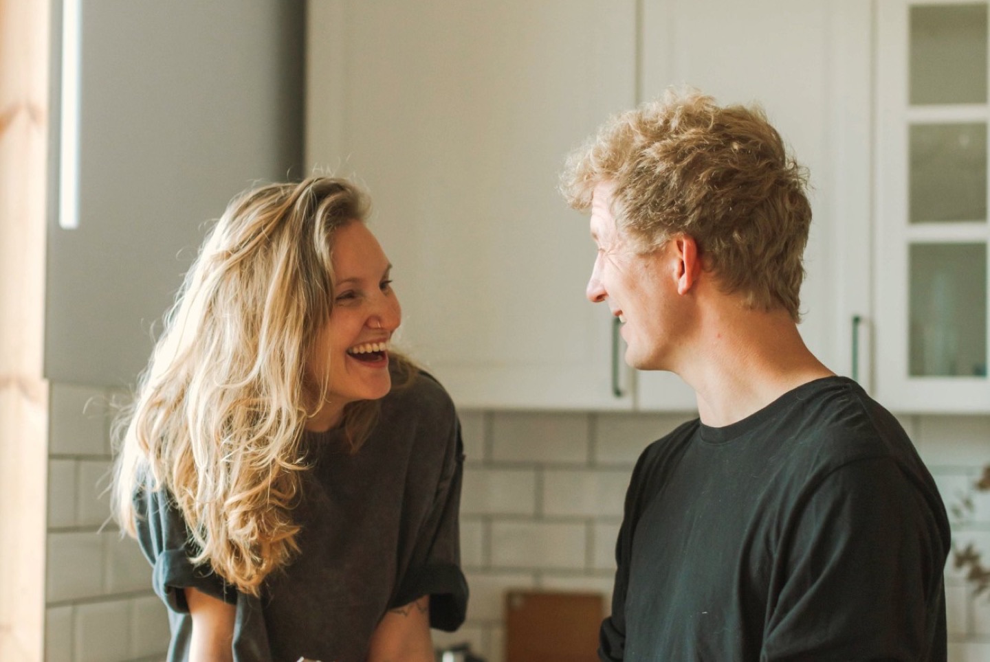 A couple laughing together while cooking at home